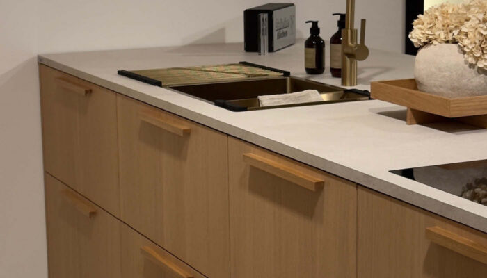 Kochinsel mit Holzfronten, Holzgriffen und weißer Steinarbeitsplatte.