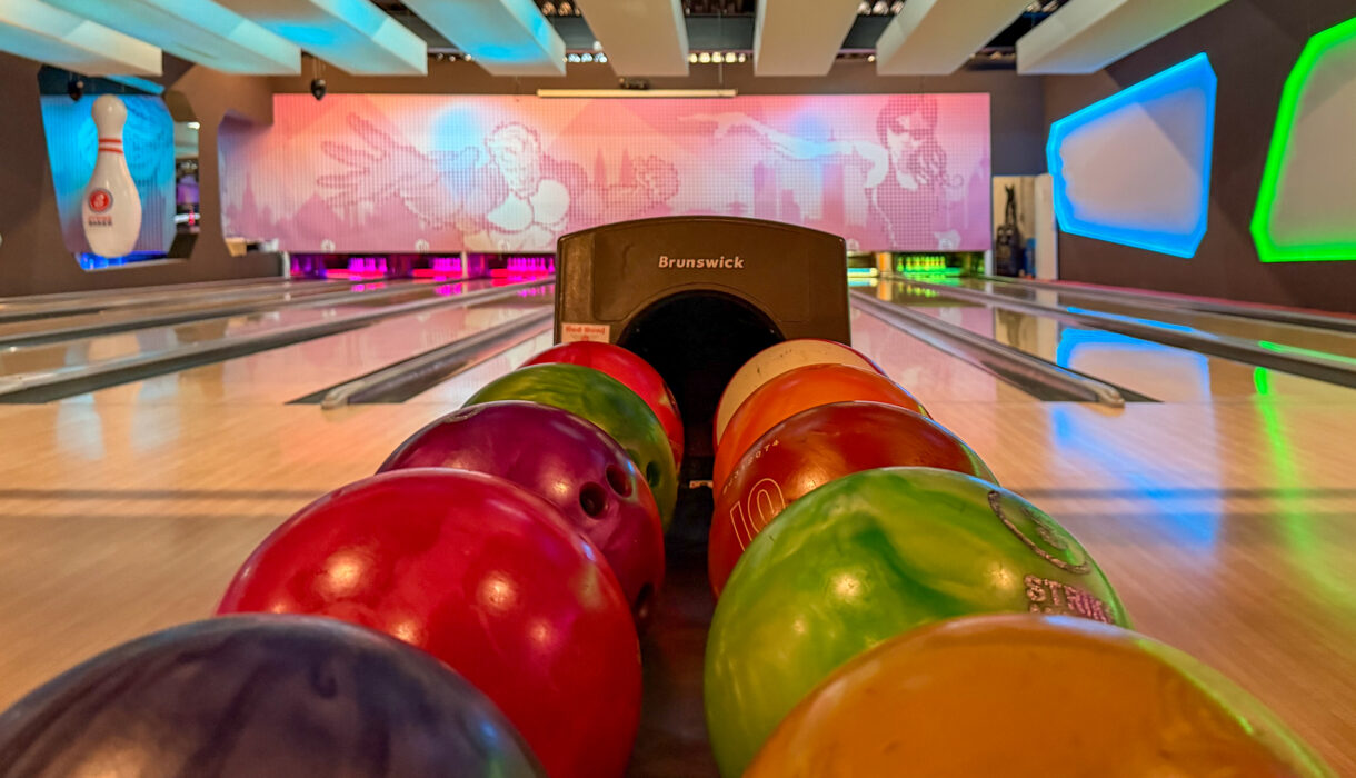 Mehrere bunte Bowlingkugeln in einer Bowlingbahn