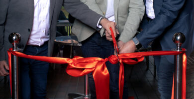 Rote Schleife wird von den Geschäftsführern mit einer Schere bei der Neueröffnung des MöFa Schulungsraumes durchgeschnitten