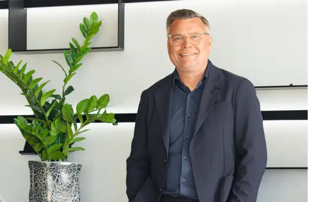 Geschäftsführer Jürgen Feldmann lächelnd neben einer Pflanze.