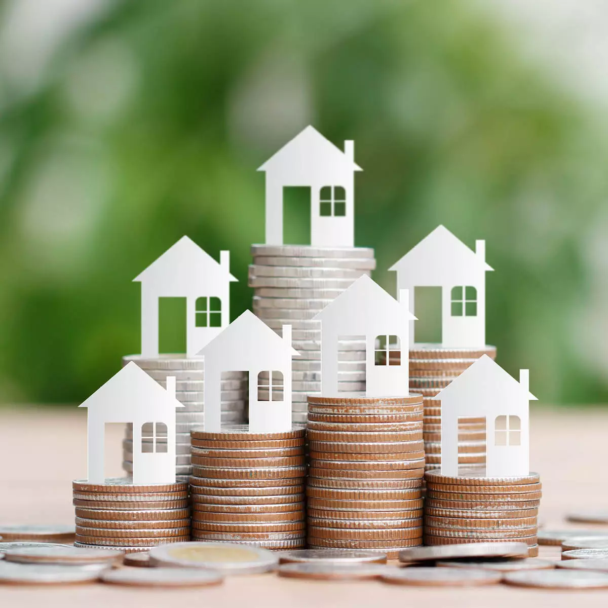 Kleine dekorative Häuser sind auf kleinen Stapeln von Münzen platziert | Marketing in Neubaugebieten