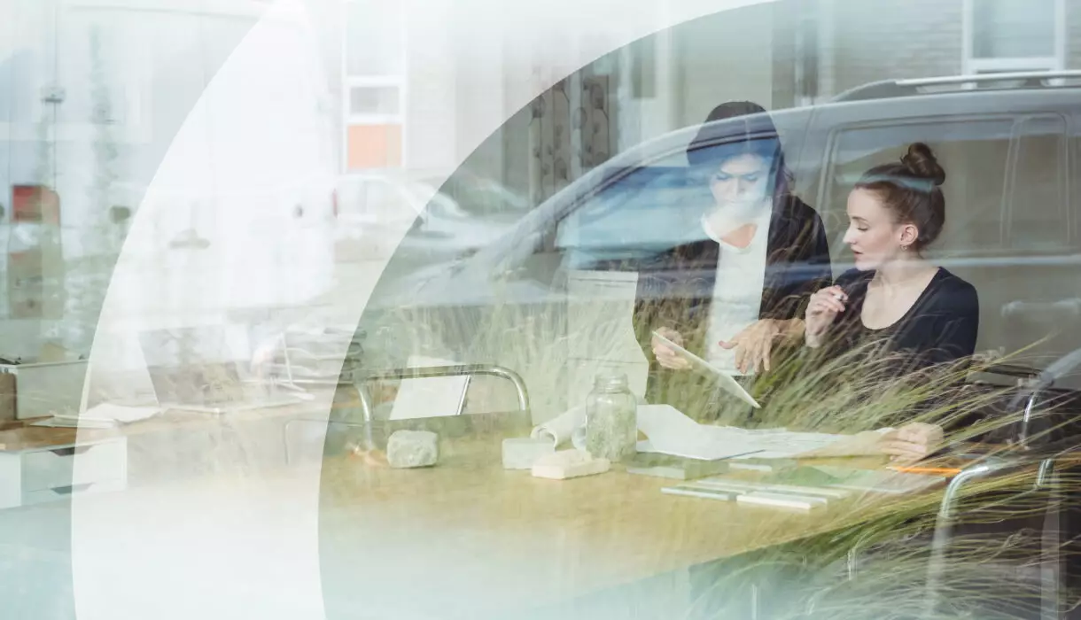 Zwei Personen im modernen Büro bei der Projektplanung, aufgenommen durch eine Glasfassade – Symbol für Transparenz und Zusammenarbeit bei Der Küchenring.